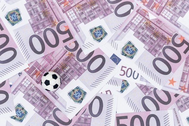 small black and white soccer ball on the background of paper money with a face value of five hundred euro