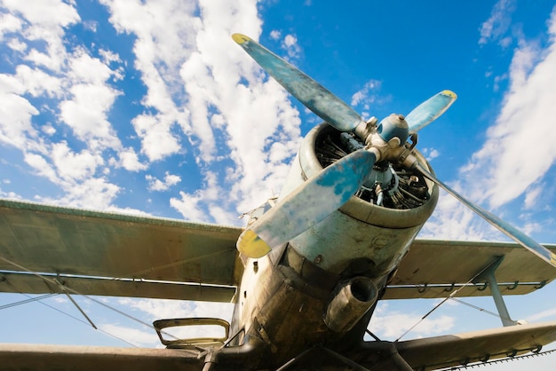 Small blue and white plane on a background of green grass and blue sky