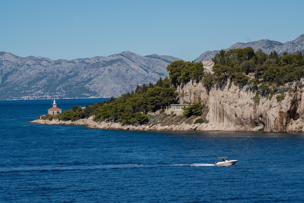 A small boat enters a picturesque port The mountains are covered with greenery the blue transparen