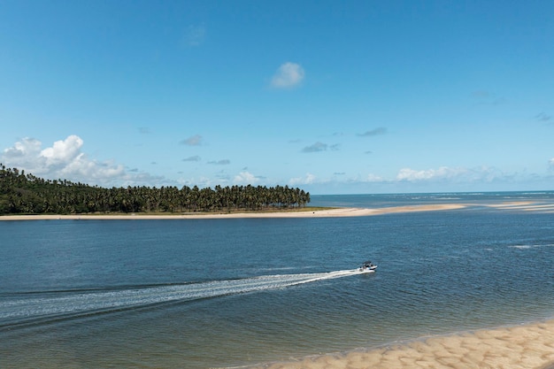 Small boat sailing in place where the river meets the sea