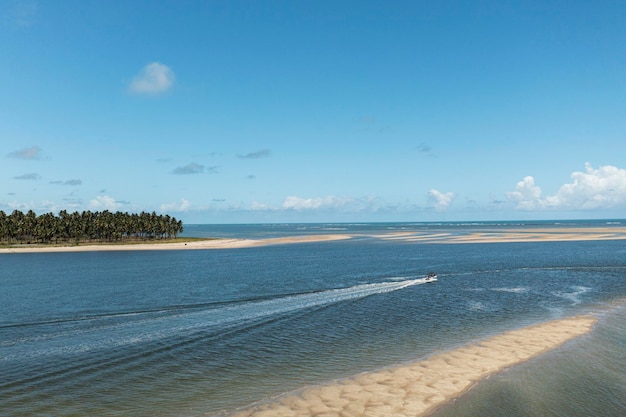 Small boat sailing in place where the river meets the sea