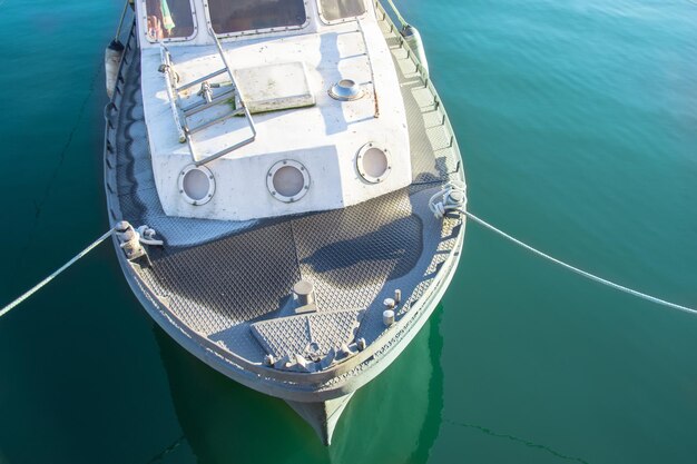 Small boat vessel moored to the pier by ropes