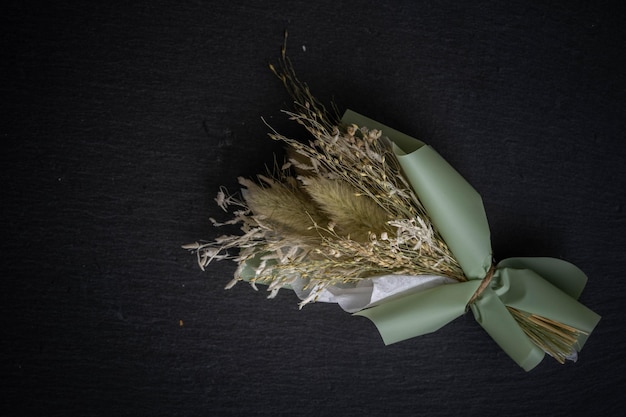 Small bouquet of dried flowers on a black background in green colors, incredible art