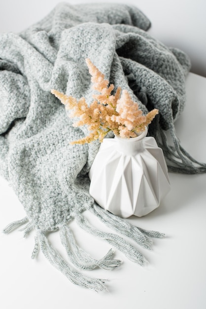 Small bouquet of flowers in vase with blanket