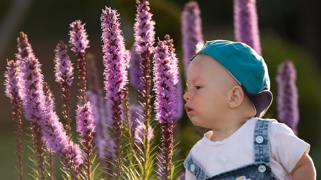 A small brightly dressed boy is playing with large purple flowers in the backyard