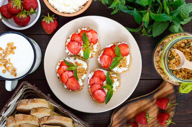 Small bruschetta with curd and fresh strawberries with mint