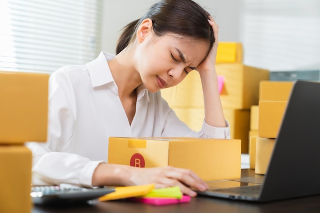 Small business, asian woman headache because there is a problem in management, delivery with packaging.