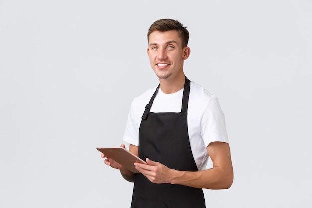 Small business coffee shop and cafe employees concept handsome waiter barista wearing apron taking o...