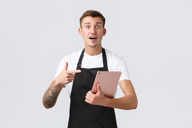 Small business coffee shop and cafe employees concept handsome worried waiter or barista in store po...