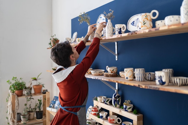 Small business female owner putting plate at right place in pottery studio