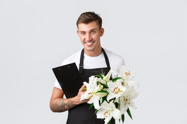 Photo small business retail and employees concept handsome salesman delivery guy from flower shop holding ...