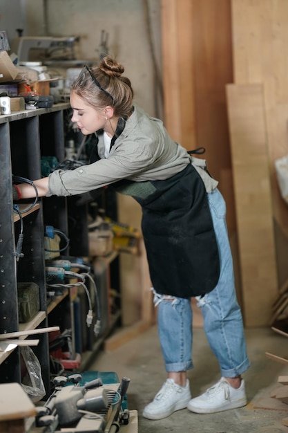 Small business of a young woman Beautiful young woman worker in a furniture workroom measuring wood