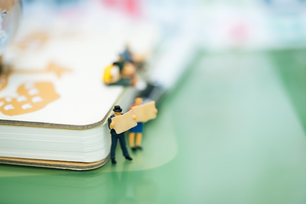 Small businessmen reading newspaper and standing in front of notebook.