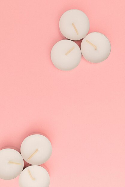 Small candles in metal jars on a pink background for use in the absence of light