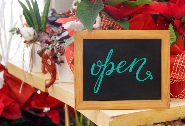 Small chalkboard with text OPEN inside a Flower shop during Christmas holiday season