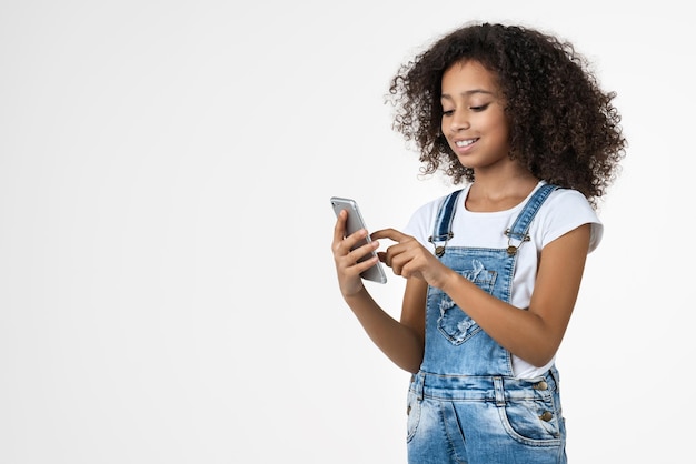 Small cheerful preteen girl using mobile phone isolated on white background