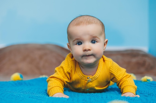 A small child 45 months old lies on a bed in yellow clothes The child begins to hold his head Baby clothes