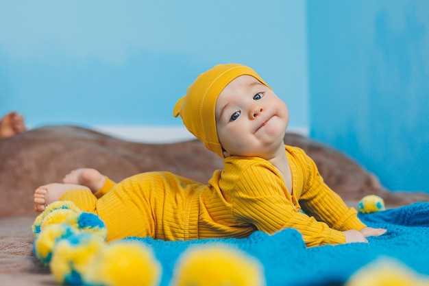 A small child 45 months old lies on a bed in yellow clothes The child begins to hold his head Baby clothes