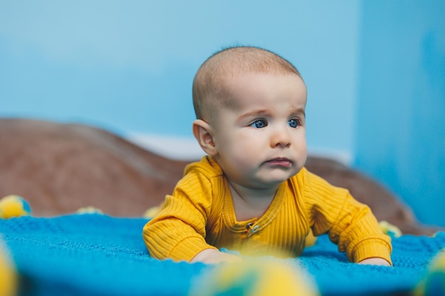 A small child 45 months old lies on a bed in yellow clothes The child begins to hold his head Baby clothes