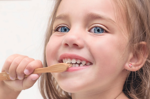 Small child brushes teeth with a bamboo toothbrush