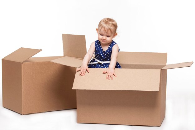 A small child in cardboard boxes on white surface