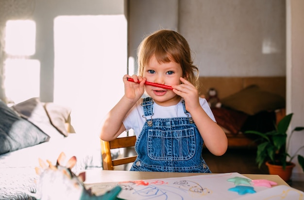 Small child at home at the childrens table draws with felttip pens