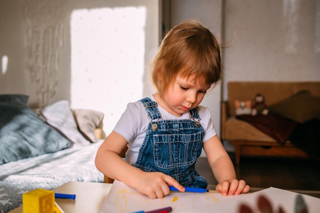 Small child at home at the childrens table draws with felttip pens