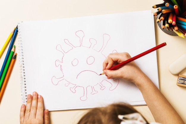 A small child in home quarantine draws a coronavirus