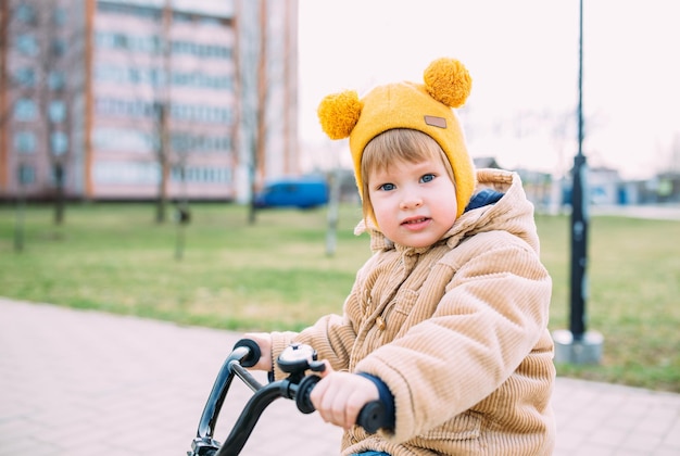 A small child learns to ride a bike for the first time in the city in spring