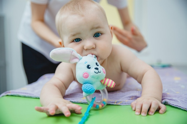 A small child lying on his stomach gets a massage in a massage room he has a toy in his mouth