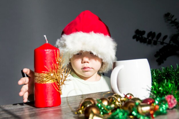 A small child in a Santa Claus hat with gifts at the New Year's table