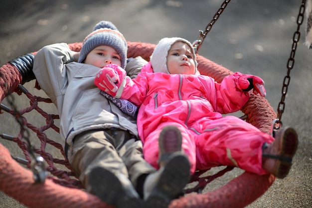 Small children boy and girl ride on a swing