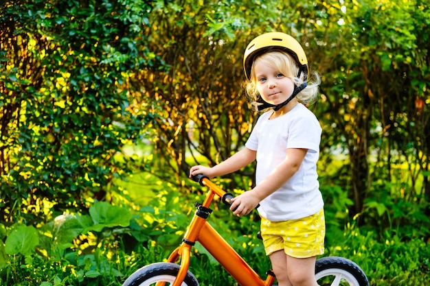 Small children girl with helmets and balance bike outdoors playing