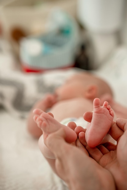 Small children's feet are lying on the bedspread. Cute newborn concept