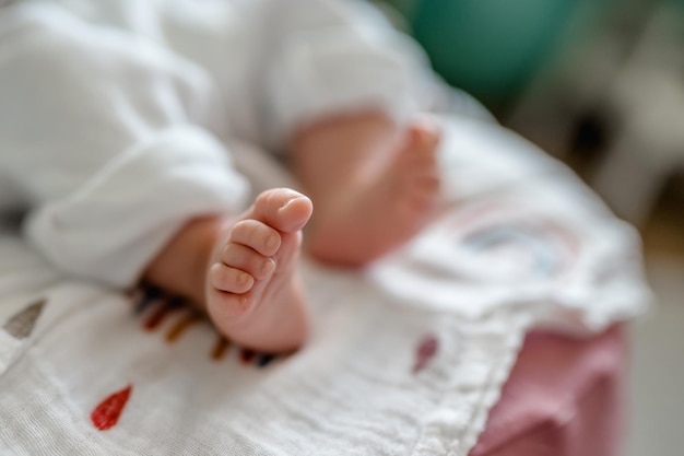 Small children's feet are lying on the bedspread. Cute newborn concept