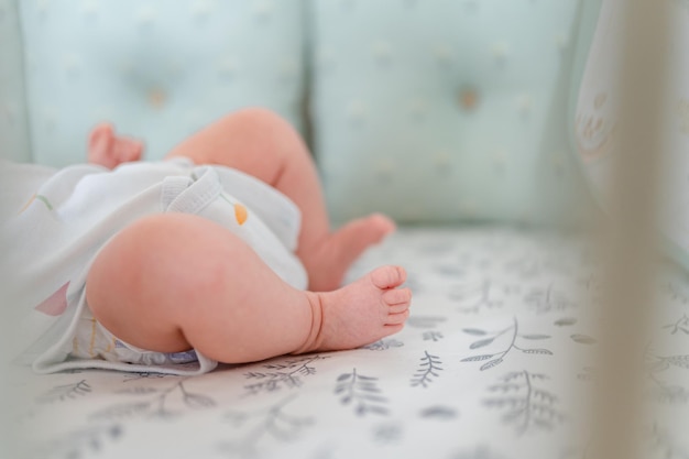 Small children's feet are lying on the bedspread. Cute newborn concept