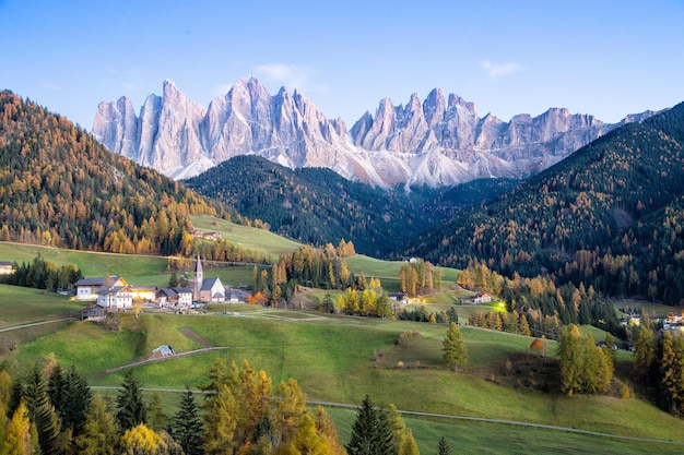 Small church front of Dolomite mountains in Autumn season.