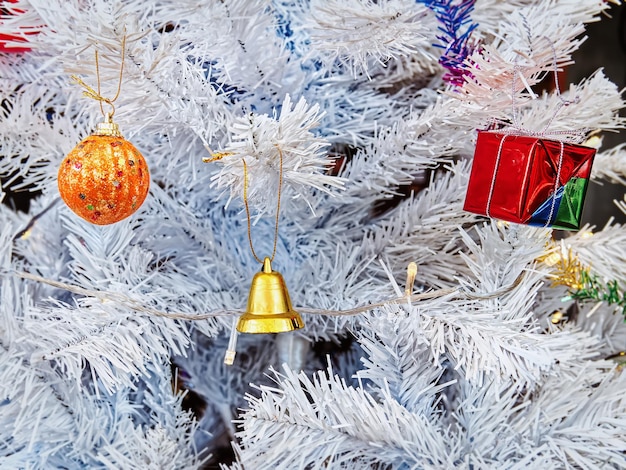 Small Colorful Hanging Giftbox and Golden Bell on White Christmas Tree