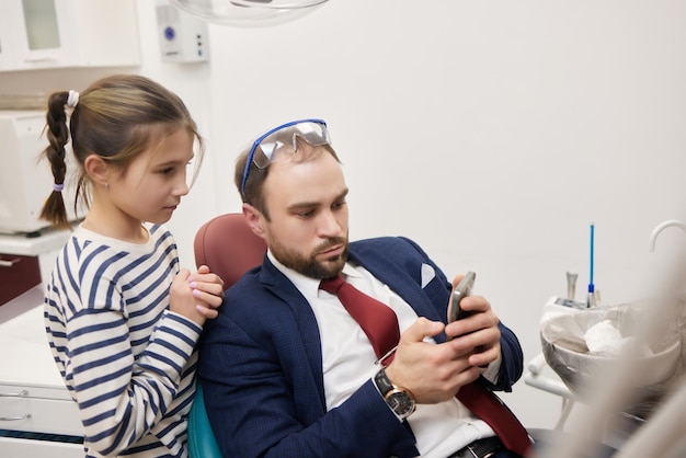 A small curly girl and her father play a dentist happy relationship