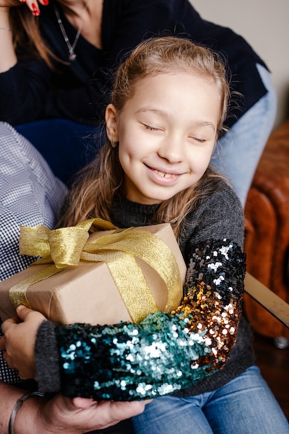 Small cute happy girl hugging her christmas present. Child excited about unpacking her gift