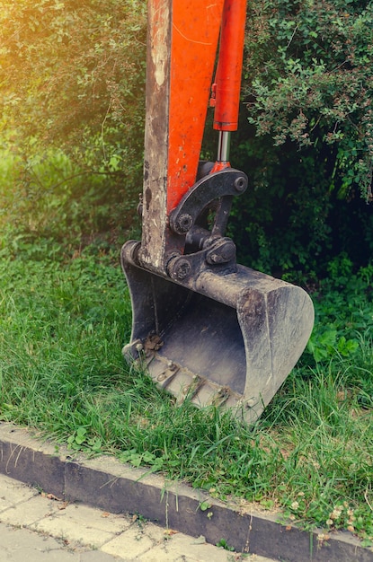 Small excavator on sidewalk near lawn Repair in city urban