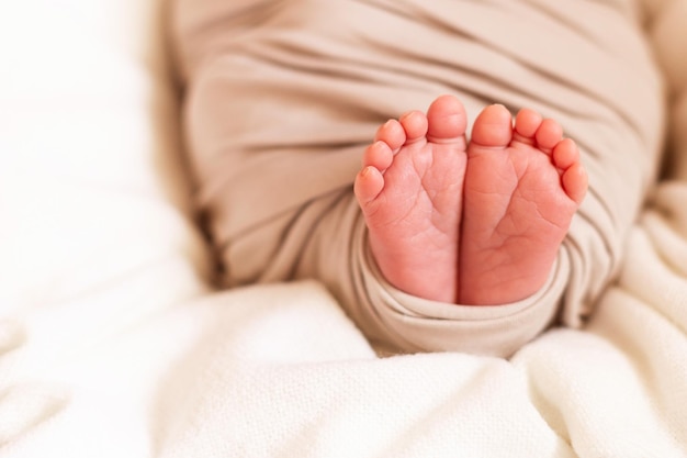 Small feet of the child closeup. Baby wrap. Sleeping newborn baby in a basket.