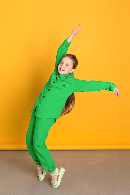 A Small Female Model Cute smiling girl with long hair looking into the camera standing isolated on the yellow background of the studio a space for copying