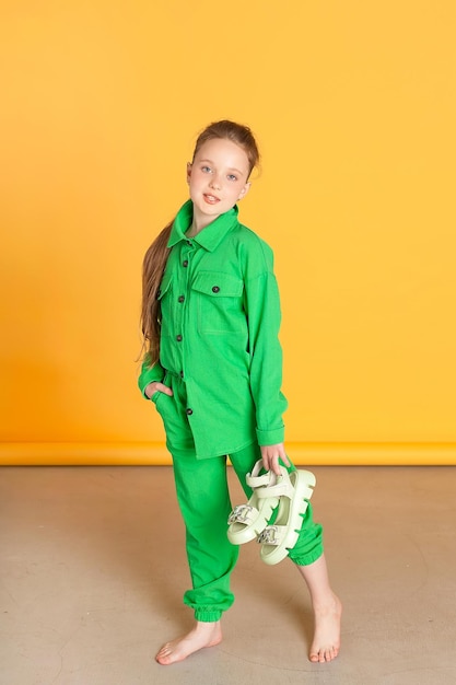 A Small Female Model Cute smiling girl with long hair looking into the camera standing isolated on the yellow background of the studio a space for copying