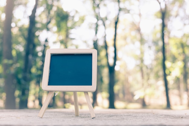 Small A-frame blackboard with blank area for text or message on rustic wood table in morning time