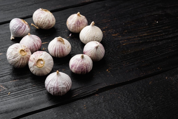 Small fresh garlic on black wooden table background with copy space for text