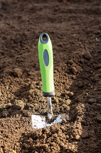 Small garden shovel stuck in ground closeup