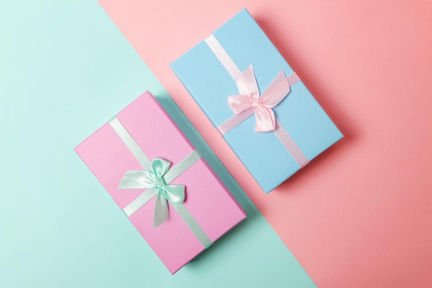 Small gift box wrapped pink and blue paper isolated on blue and pink pastel colorful trendy geometric background Christmas New Year birthday valentine celebration present romantic concept