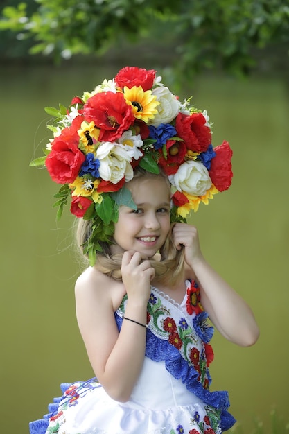 Small girl in embriodered dress and flower national wreath