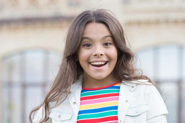 Small girl gorgeous hairstyle adorable smile urban background joyful day concept